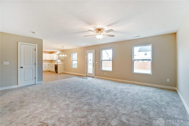 unfurnished living room with ceiling fan with notable chandelier and light colored carpet