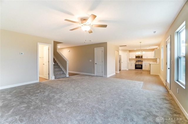 unfurnished living room with ceiling fan, sink, and light carpet