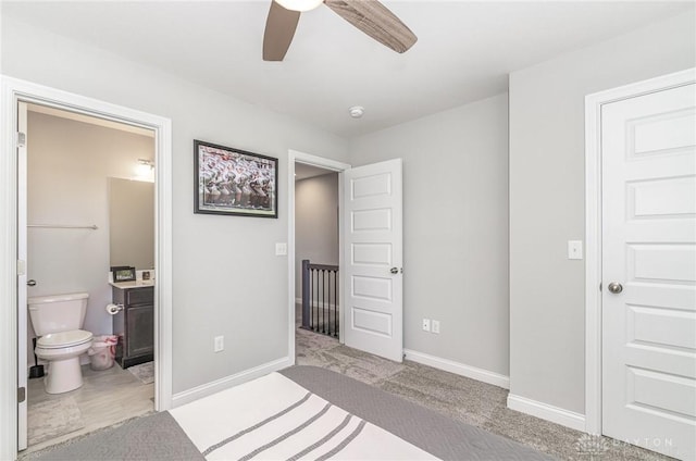 bedroom with ceiling fan, light colored carpet, and ensuite bathroom