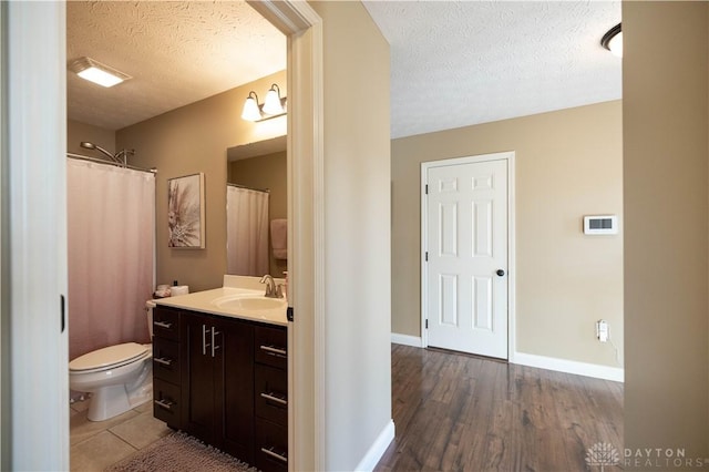 bathroom with hardwood / wood-style flooring, vanity, toilet, and a textured ceiling