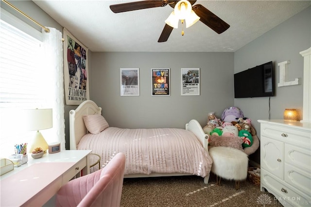 carpeted bedroom featuring ceiling fan and a textured ceiling