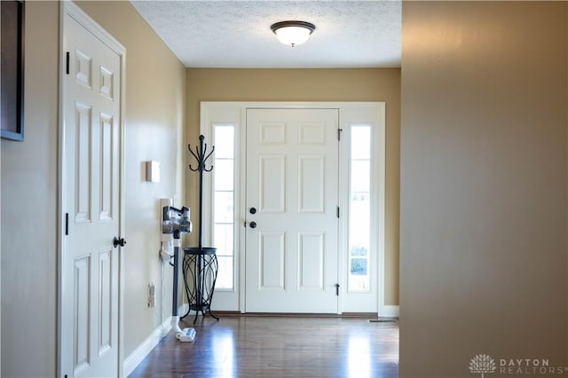 foyer entrance with dark hardwood / wood-style flooring and a textured ceiling