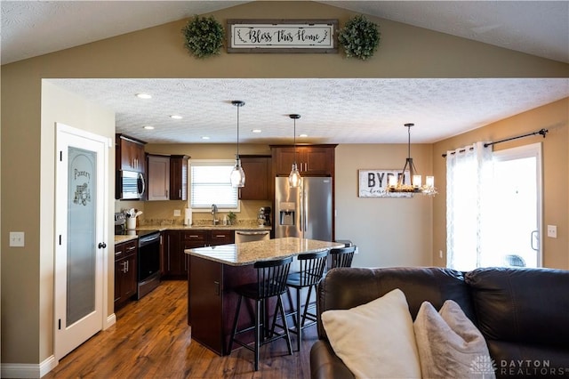 kitchen with sink, a breakfast bar area, appliances with stainless steel finishes, a kitchen island, and pendant lighting