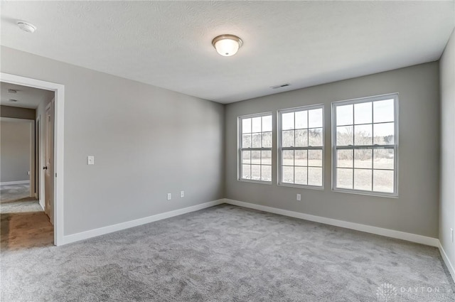 carpeted empty room featuring a textured ceiling