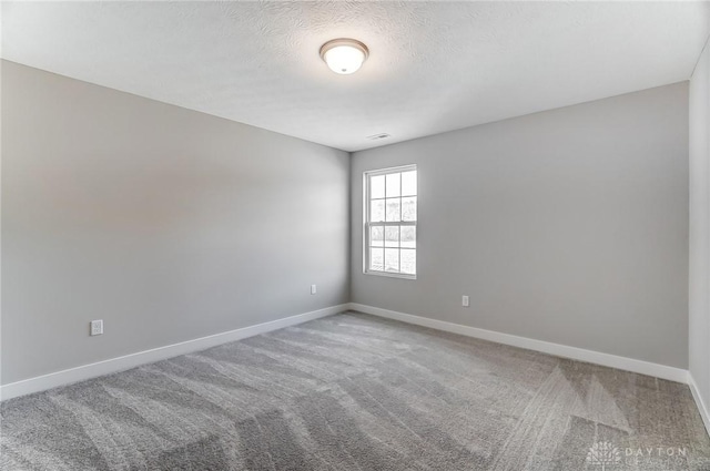 carpeted empty room with a textured ceiling