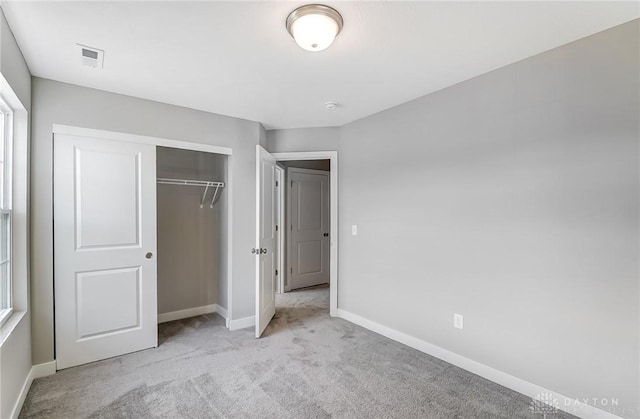 unfurnished bedroom featuring light colored carpet and a closet