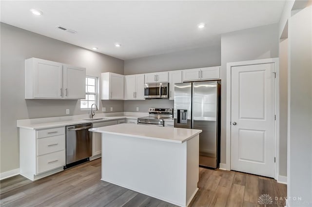 kitchen with sink, light hardwood / wood-style flooring, white cabinetry, stainless steel appliances, and a center island