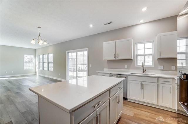 kitchen featuring sink, dishwasher, white cabinetry, hanging light fixtures, and a center island