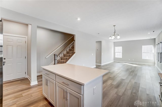 kitchen featuring hanging light fixtures, a center island, a chandelier, and light hardwood / wood-style flooring