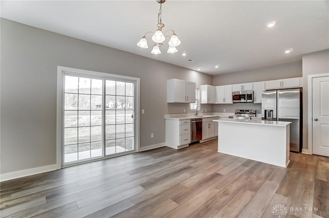 kitchen with pendant lighting, white cabinetry, sink, a center island, and stainless steel appliances