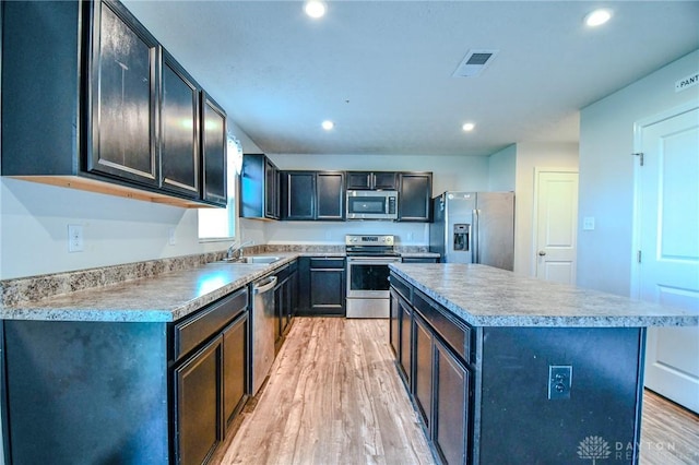 kitchen with stainless steel appliances, a center island, sink, and light wood-type flooring