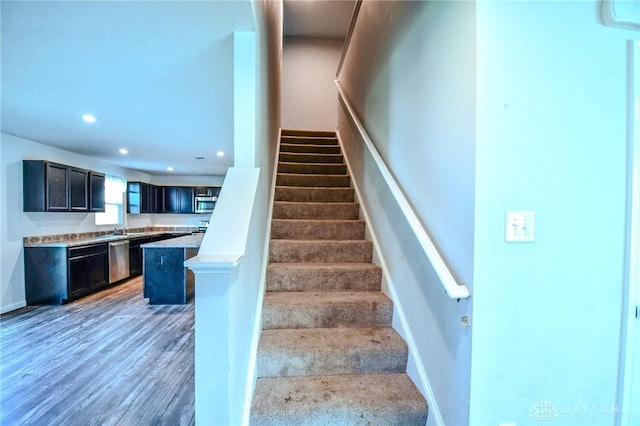 staircase with sink, hardwood / wood-style floors, and an AC wall unit