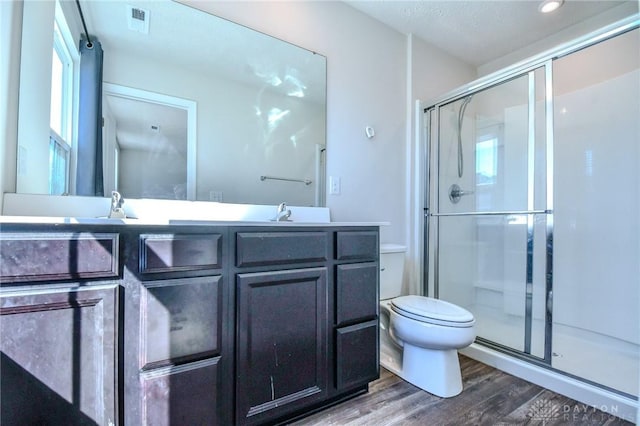 bathroom with hardwood / wood-style flooring, vanity, toilet, and a shower with shower door