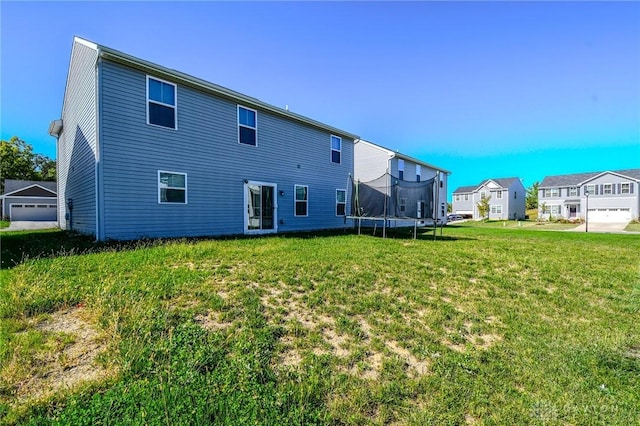 rear view of property with a trampoline and a lawn