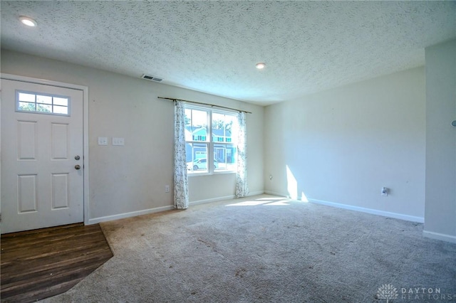 carpeted foyer entrance with a textured ceiling