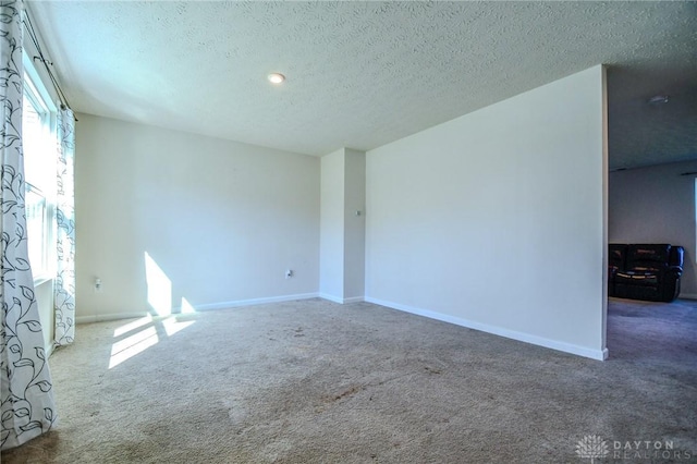 carpeted empty room featuring a textured ceiling