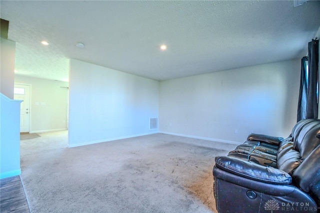 sitting room with dark carpet and a textured ceiling