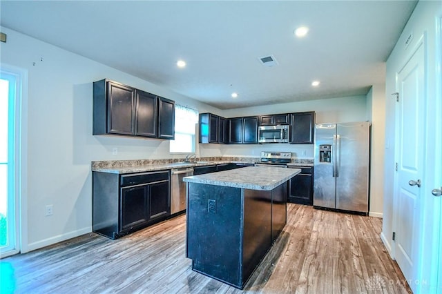 kitchen featuring stainless steel appliances, sink, a center island, and light hardwood / wood-style floors