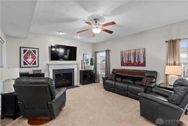 carpeted living room featuring ceiling fan and a textured ceiling