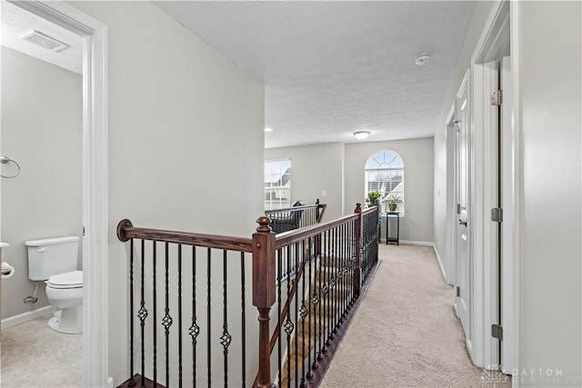 hall with light carpet and a textured ceiling