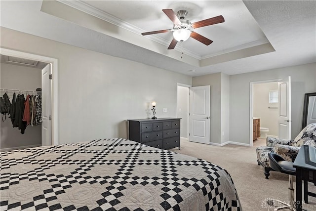 bedroom with crown molding, a tray ceiling, a walk in closet, light colored carpet, and a closet