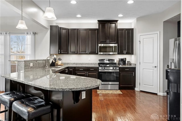 kitchen with pendant lighting, sink, a breakfast bar area, stainless steel appliances, and kitchen peninsula