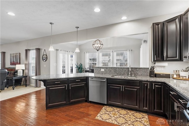 kitchen with sink, light stone counters, decorative light fixtures, dishwasher, and kitchen peninsula