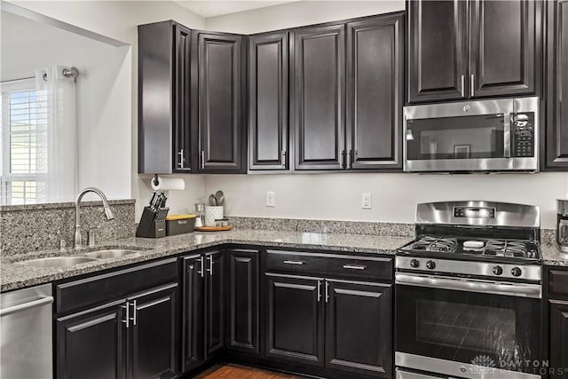 kitchen featuring light stone countertops, appliances with stainless steel finishes, and sink