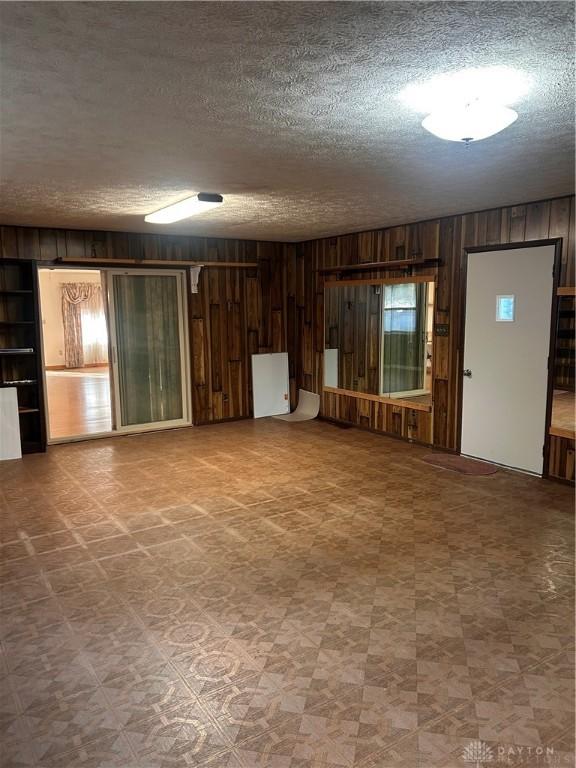 unfurnished living room with wooden walls and a textured ceiling