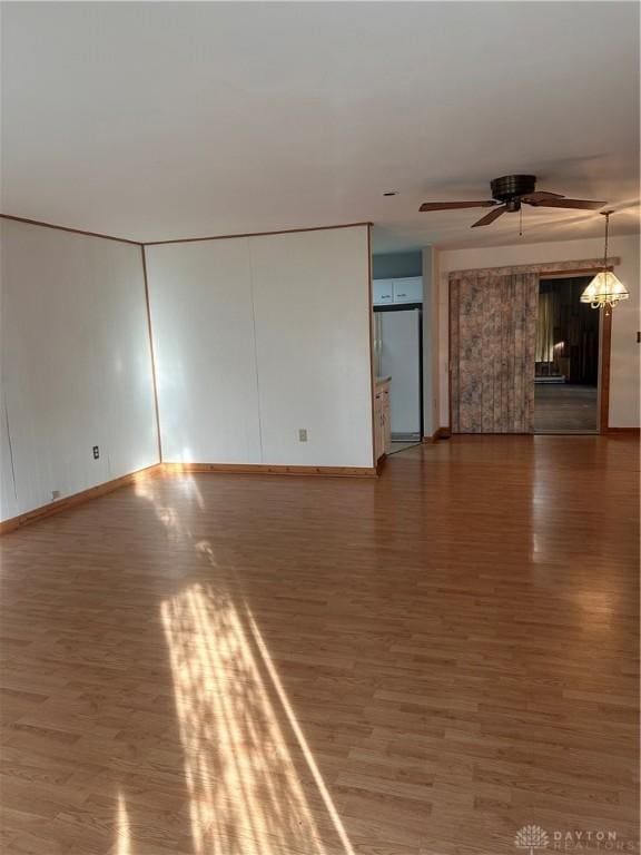 empty room with wood-type flooring and ceiling fan with notable chandelier