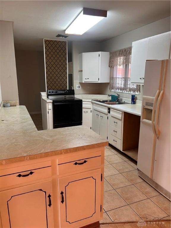 kitchen with white cabinetry, sink, white refrigerator with ice dispenser, light tile patterned floors, and black range with electric stovetop