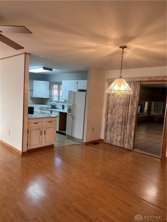 kitchen with dishwasher, white cabinetry, hanging light fixtures, white fridge with ice dispenser, and light wood-type flooring