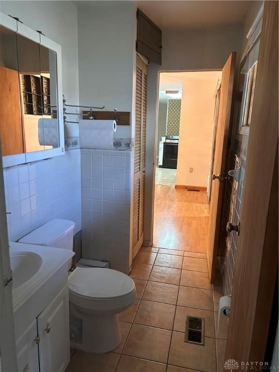 bathroom with vanity, toilet, tile patterned flooring, and tile walls