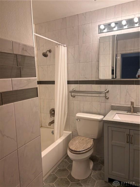 full bathroom with shower / tub combo with curtain, toilet, tile walls, vanity, and tile patterned flooring