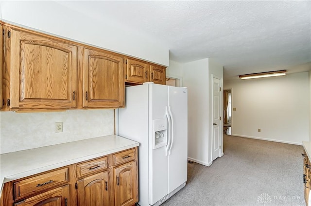 kitchen featuring a textured ceiling, white fridge with ice dispenser, and light carpet