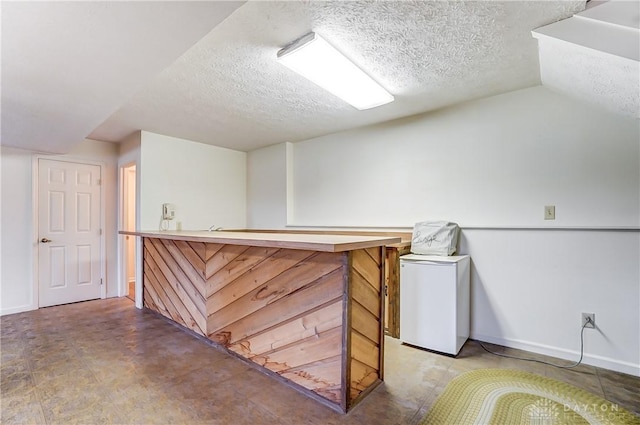 bar with vaulted ceiling and a textured ceiling