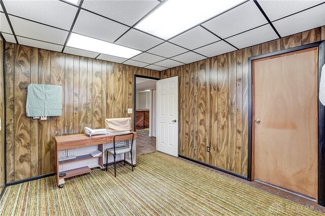 carpeted office space featuring a paneled ceiling and wooden walls