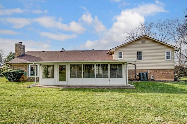 rear view of house with central air condition unit, a sunroom, and a yard