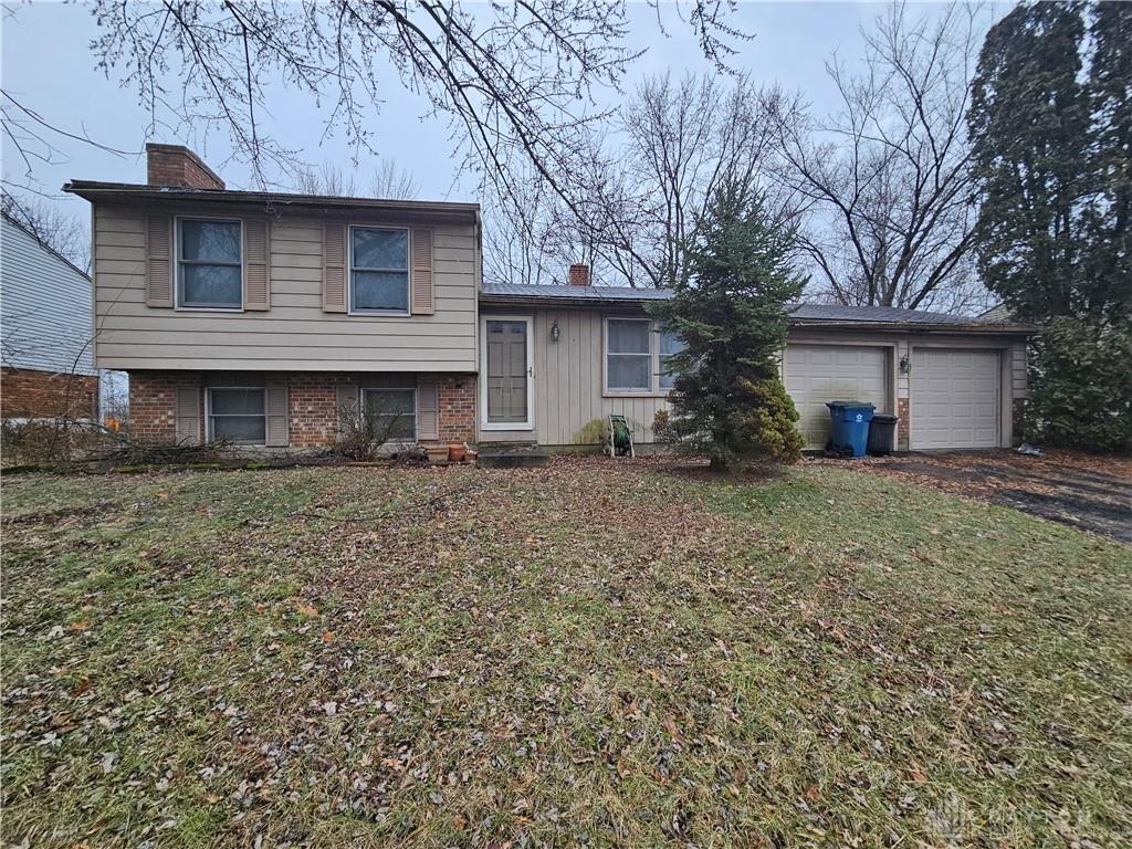 tri-level home featuring a garage and a front lawn