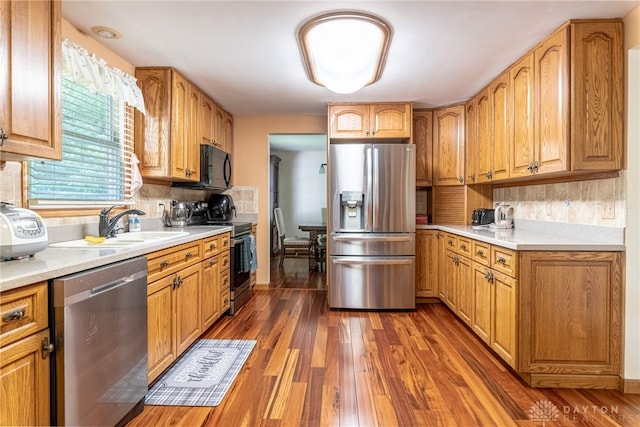 kitchen with stainless steel appliances, dark wood-type flooring, sink, and backsplash