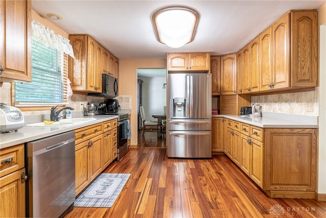 kitchen with stainless steel appliances, dark wood-style floors, light countertops, and a sink