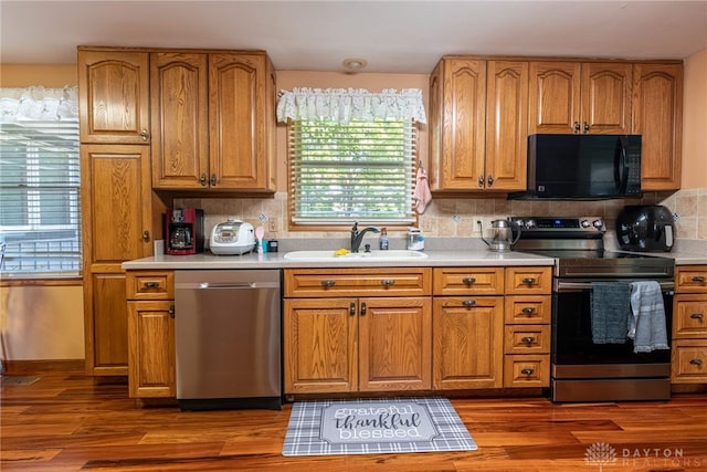 kitchen featuring appliances with stainless steel finishes, sink, dark wood-type flooring, and backsplash