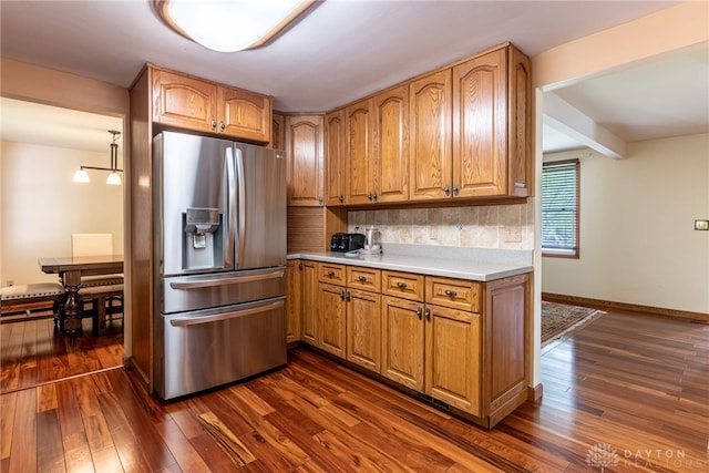 kitchen featuring stainless steel refrigerator with ice dispenser, decorative backsplash, dark wood finished floors, and light countertops