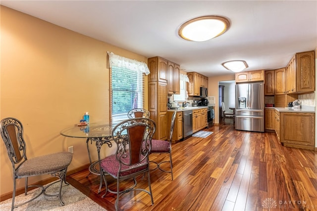 kitchen featuring stainless steel appliances, dark wood-style flooring, brown cabinets, and light countertops