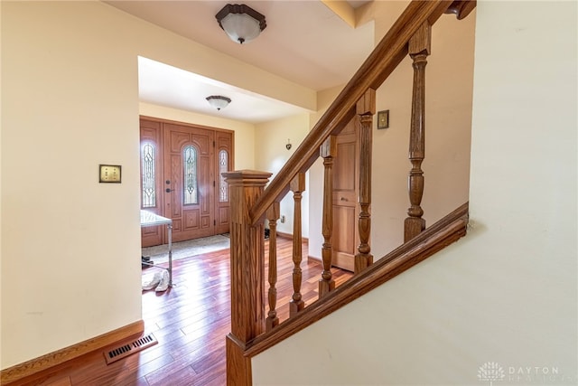 entryway featuring wood finished floors, stairs, and baseboards