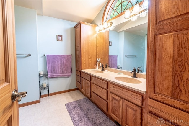 full bathroom featuring lofted ceiling, double vanity, and baseboards