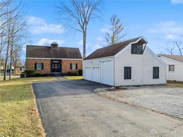 view of front facade featuring brick siding, a detached garage, an outdoor structure, a front lawn, and a chimney