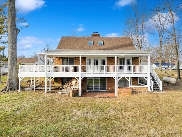 rear view of house featuring a shingled roof, a chimney, stairway, a yard, and brick siding