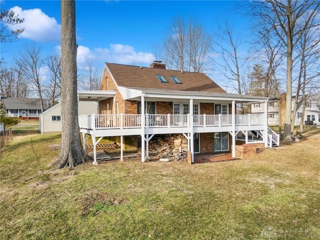 back of property with a wooden deck, a chimney, a lawn, and brick siding