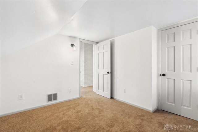 interior space featuring vaulted ceiling and light carpet